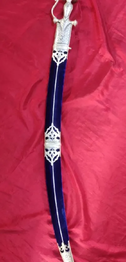 Ornate sword laid on vibrant red silk.