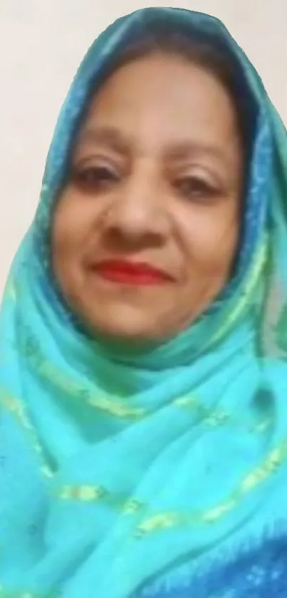 Woman with teal headscarf smiling softly.