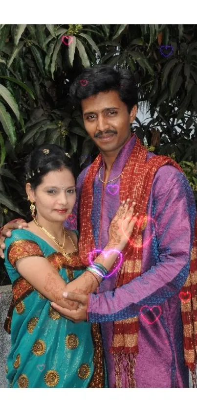 Couple in traditional attire with lush greenery backdrop.