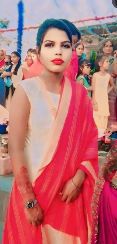 Woman in elegant red saree at a vibrant cultural event.