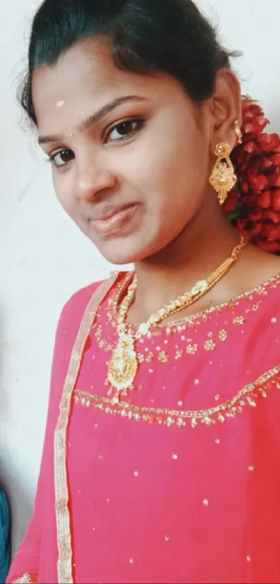 Young woman in pink traditional attire with gold accessories.