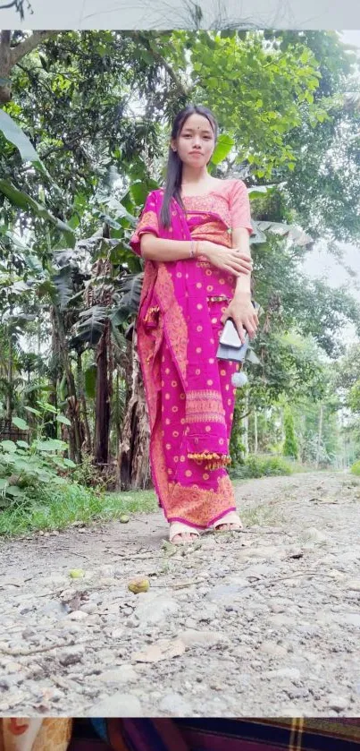 Woman in traditional attire stands on a forest path.