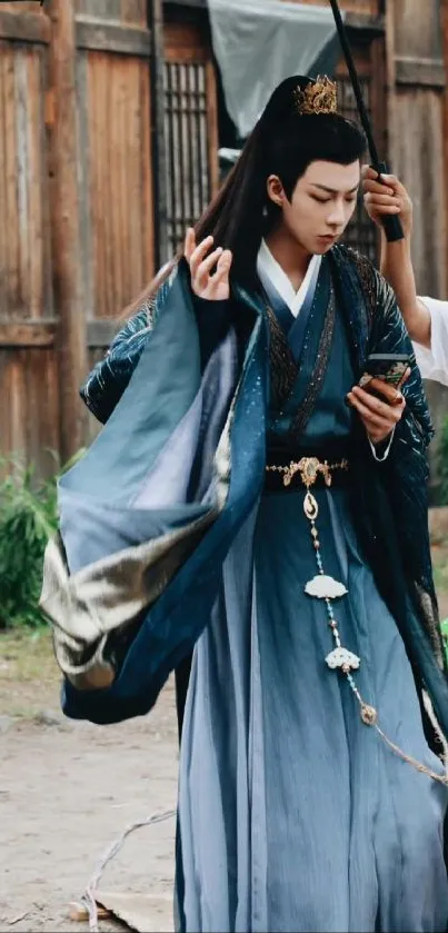 Person in elegant blue traditional attire holding a phone.