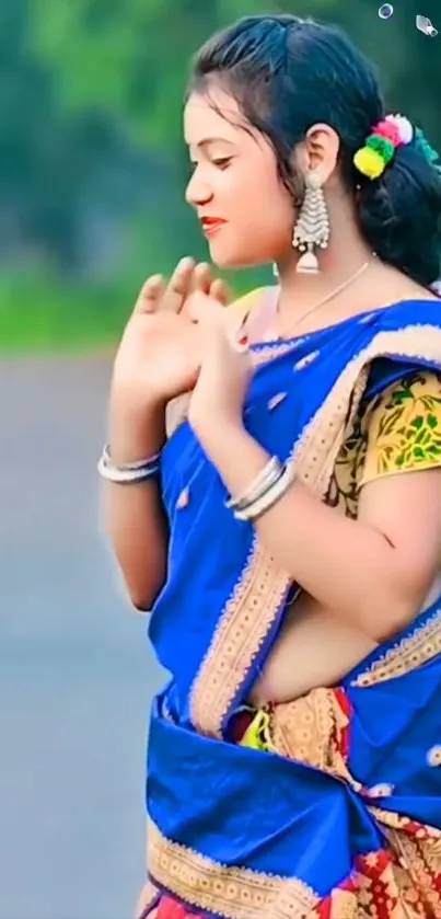 Woman in vibrant blue traditional attire with jewelry.