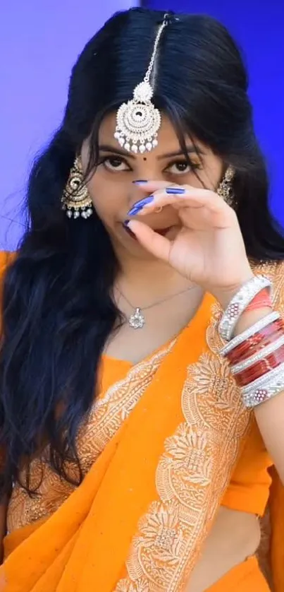 Elegant woman in orange saree with traditional jewelry.
