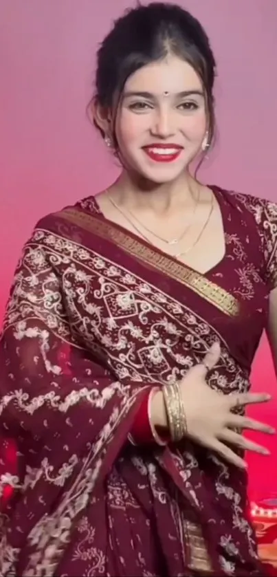 Woman in maroon traditional attire with gold motifs, smiling elegantly.