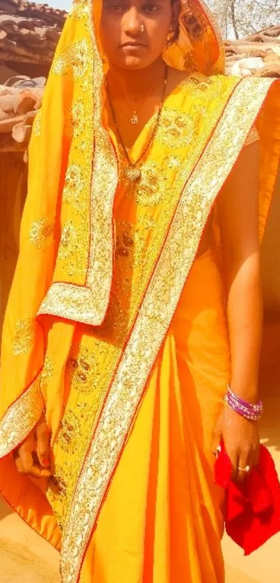 Woman in vibrant golden-orange saree with traditional Indian attire.