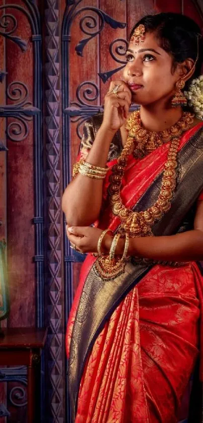 Elegant woman in traditional red saree and gold jewelry standing gracefully.