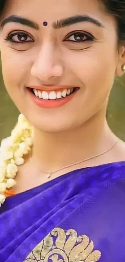 Smiling person in blue traditional attire, floral details.