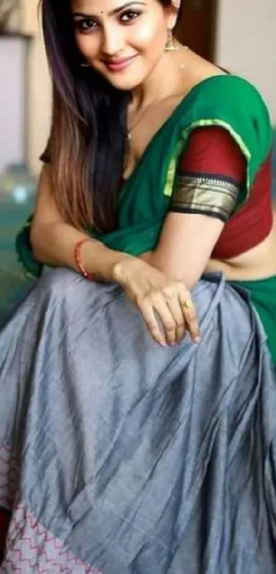 A woman elegantly dressed in a green traditional Indian saree sitting gracefully.