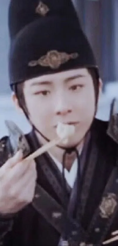 Man in traditional attire eating with chopsticks.