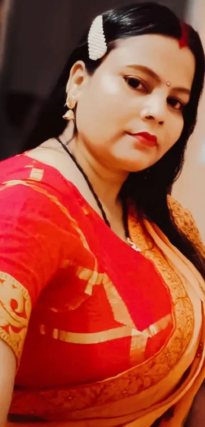 Woman in red and gold traditional saree, posing elegantly.