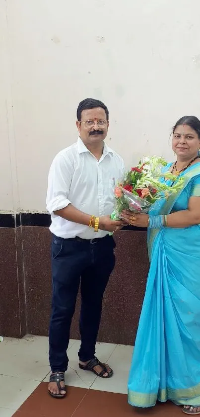 Traditional Indian couple celebrating with a flower bouquet, wearing blue attire.