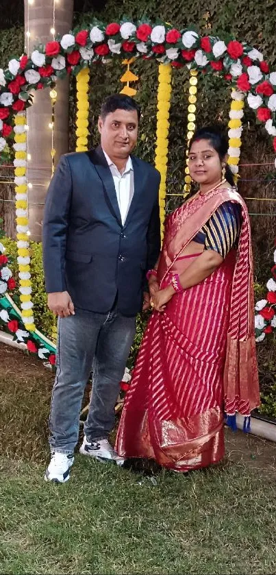 Couple in traditional attire with floral decor.