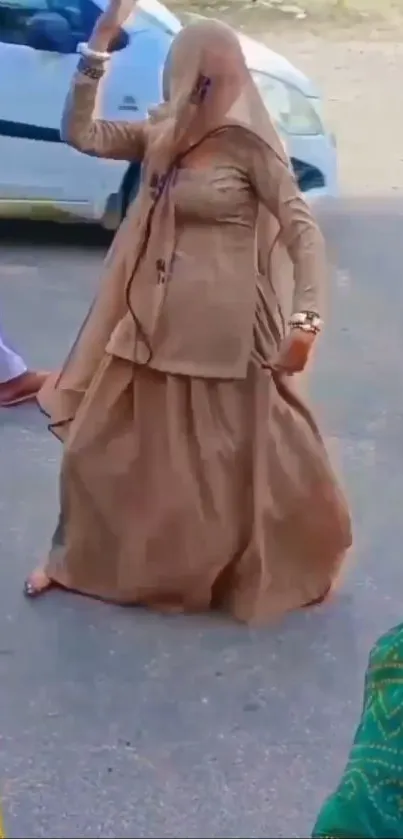 Woman dancing in brown traditional attire, outdoors scene.