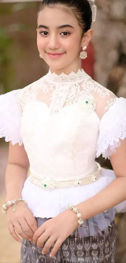 Young girl in traditional white dress with lace details, looking elegant and poised.