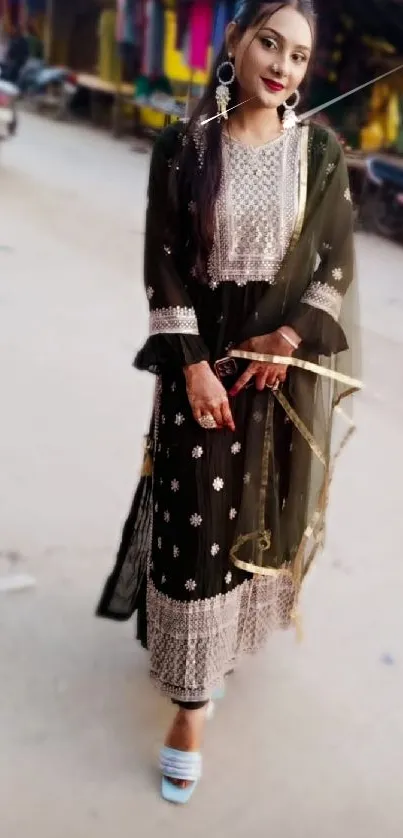 Woman in elegant traditional attire posing on a vibrant street.