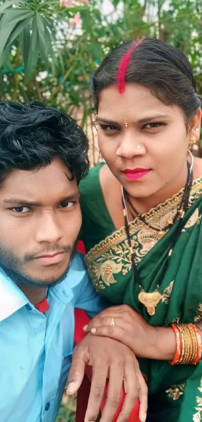 Indian couple in traditional attire, posing outside.