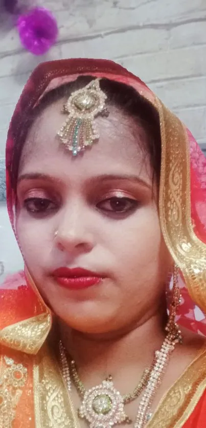 Woman in traditional attire with elegant jewelry against a brick wall.