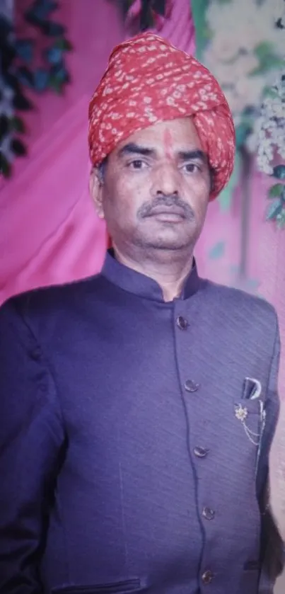 Traditional portrait with red turban and dark suit on colorful floral background.