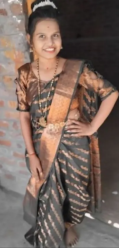 Woman in a traditional saree with a brick background.