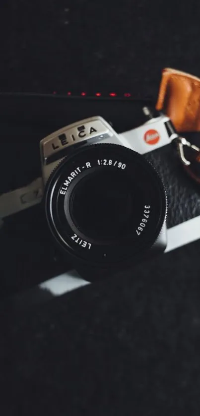 Elegant vintage camera with leather strap on a black background wallpaper.