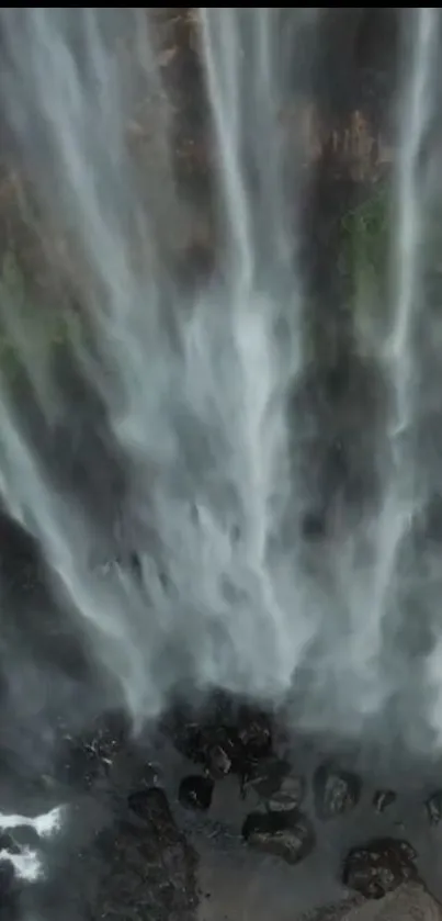 Majestic waterfall with cascading streams of water over rocks and surrounded by greenery.