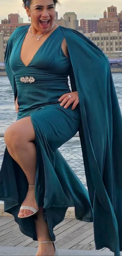 Woman in emerald dress by the waterfront, smiling.