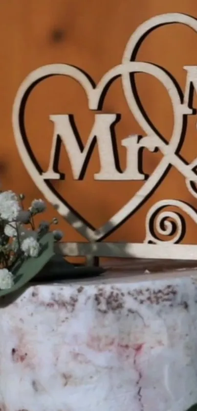 Elegant wedding cake with heart topper and floral accents.