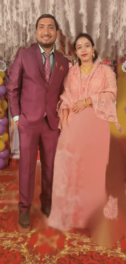 Elegant couple in wedding attire with colorful decorations in the background.