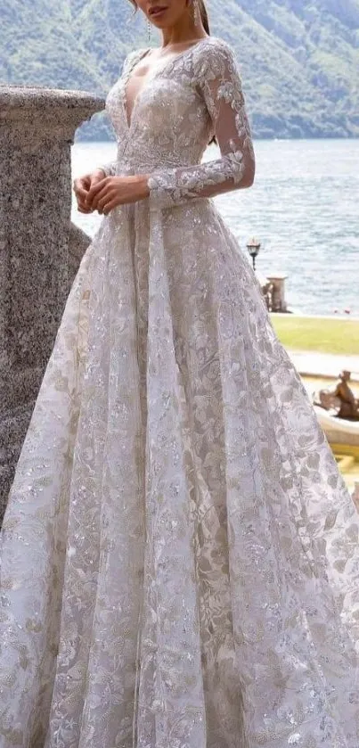 Elegant bride in detailed wedding gown by picturesque lakeside scenery.