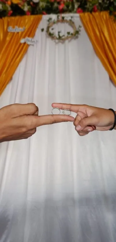 Wedding rings gesture with gold curtain backdrop.