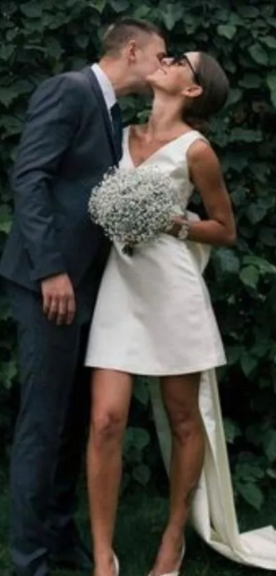 Elegant wedding couple kissing amid lush greenery.