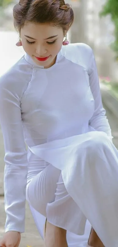 Woman in a traditional white dress sitting gracefully outdoors.