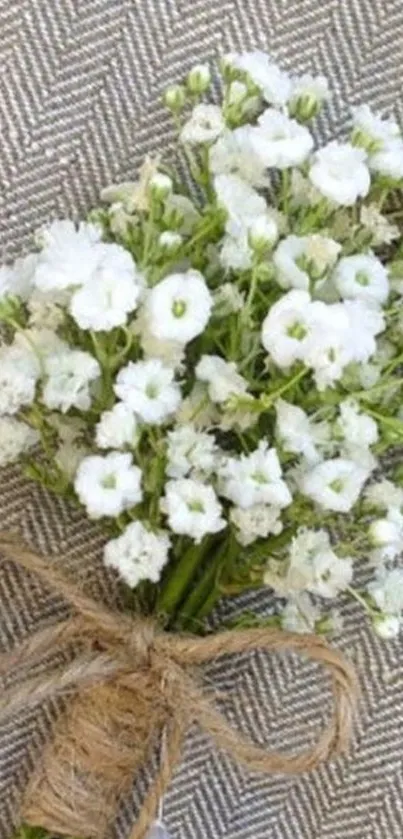 White floral bouquet with jute twine on a textured background.