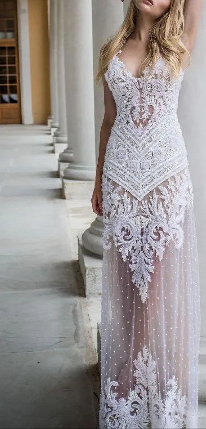 Model in elegant white lace dress in a columned hallway.