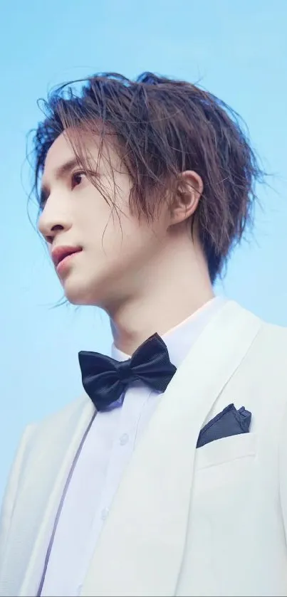 Young man in a white suit under a bright blue sky, looking stylish and elegant.