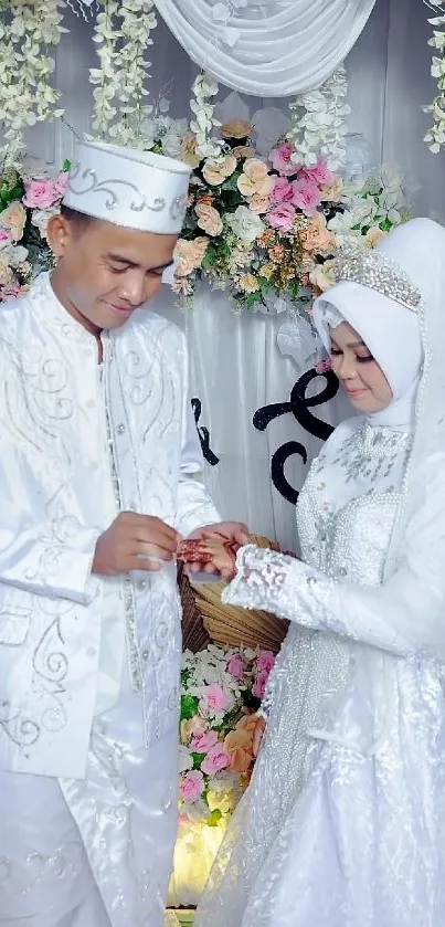 Couple in elegant white wedding attire with floral decorations.