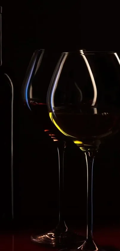 Elegant wine glasses with bottle on dark background.