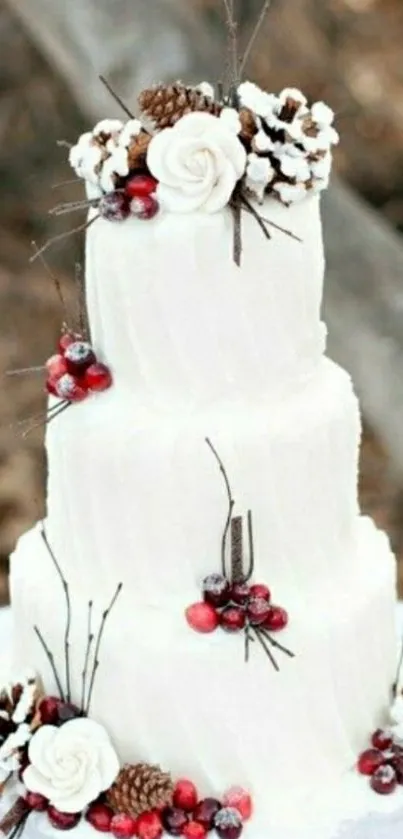 Three-tiered white cake with berries and pinecones.