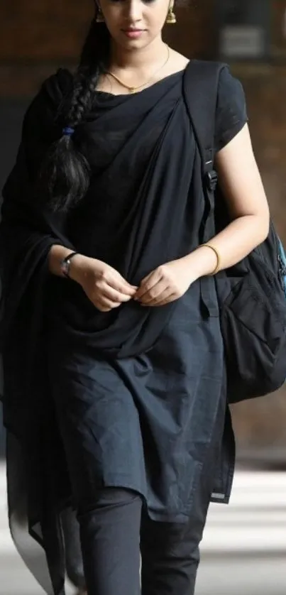 Woman in stylish black attire walking indoors.