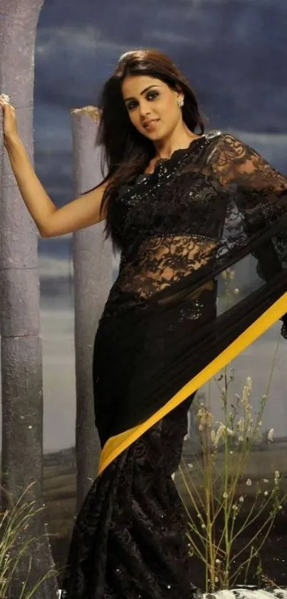 Woman in black lace saree with dramatic backdrop.