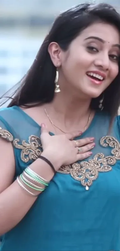 Woman wearing a blue saree with elegant embroidery, smiling cheerfully.