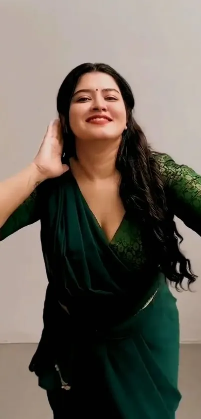 Woman in green sari poses elegantly against a plain background.