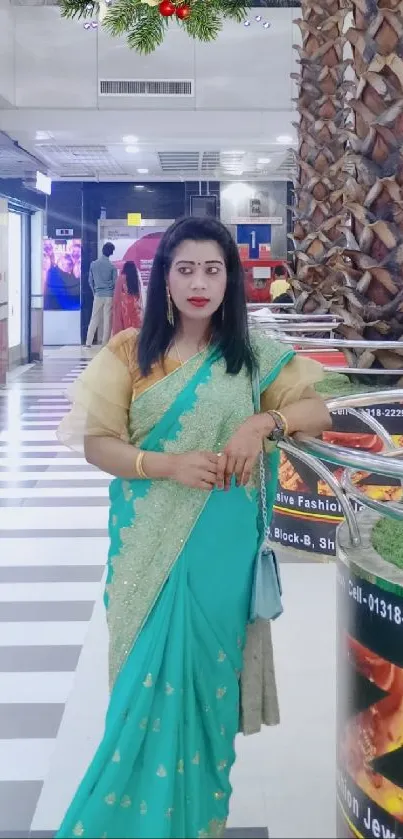 Woman wearing a green saree in a shopping mall.