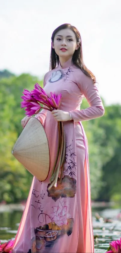 Woman in pink dress holding flowers by green backdrop.