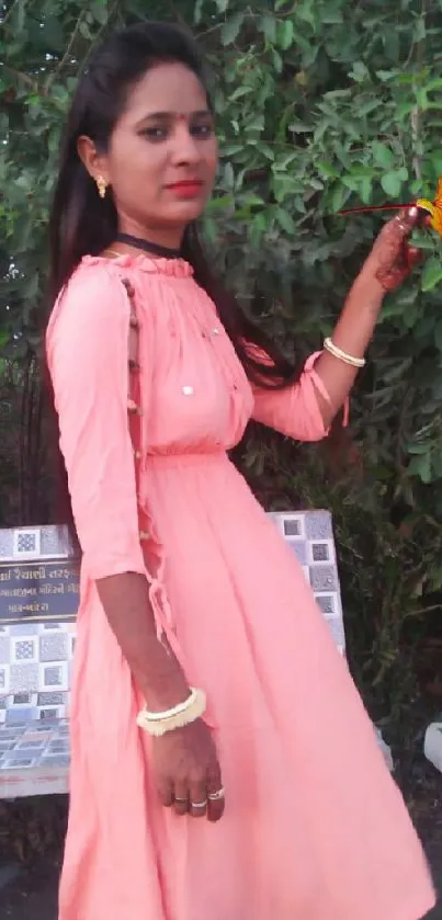 Woman in pink dress holding colorful leaves.