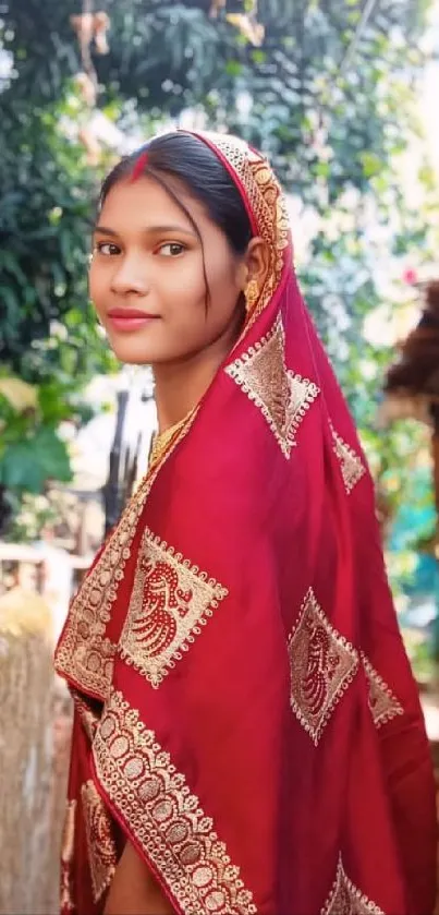 Woman in a red saree with a natural background.