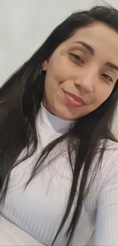 Woman with dark hair in white attire smiling confidently.