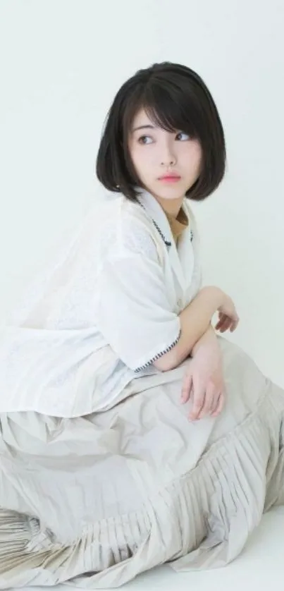 Elegant woman in white dress sitting on floor.